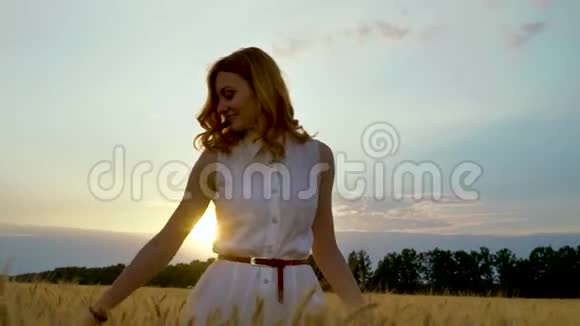 日落时麦田里的年轻女子阳光透过云层照射在背景上视频的预览图