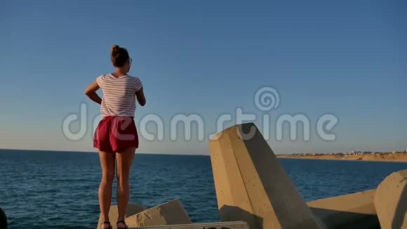 穿着短裤的漂亮女孩在海边的水泥块上跳舞视频的预览图