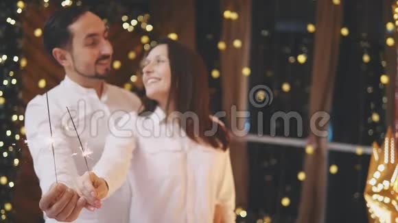 幸福的男人和女人带着孟加拉灯温柔地看着对方微笑着新年快乐视频的预览图