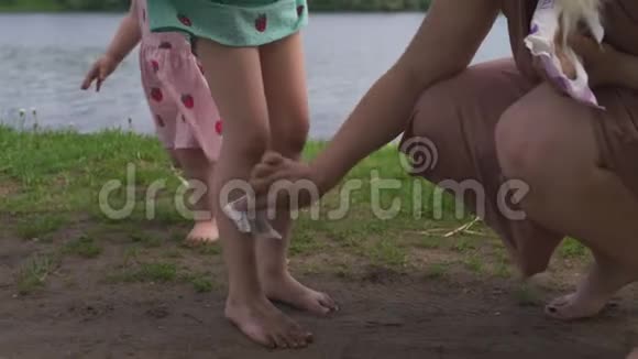 年轻的金发嬉皮士妈妈和她的小女孩在公园里清理脏腿女儿穿着视频的预览图