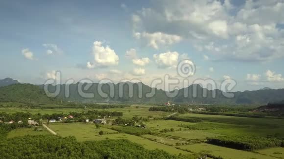 在蓝天下的田野和小镇上空飞行视频的预览图