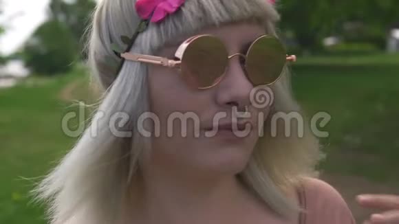 一位年轻的金发嬉皮女子戴着眼镜戴着鼻环头发上戴着洋红色的花带视频的预览图