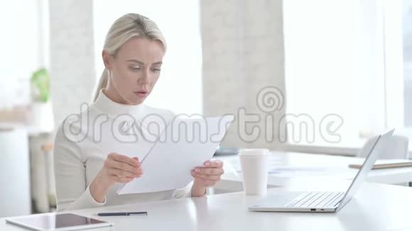 扰乱年轻女商人阅读办公室文件视频的预览图