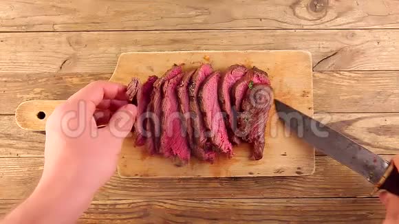 男人的手在木板上放刀切片烤中熟的烤牛肉视频的预览图