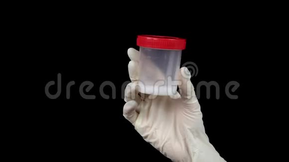 精子在一个测试库的特写医生把一个罐子装在一个黑色背景的手套里视频的预览图