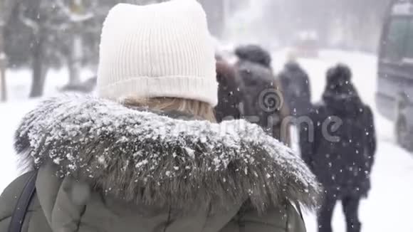 雪慢慢地落在女孩帽子和夹克上城市里的女孩在等待冬天的交通背景慢的莫视频的预览图