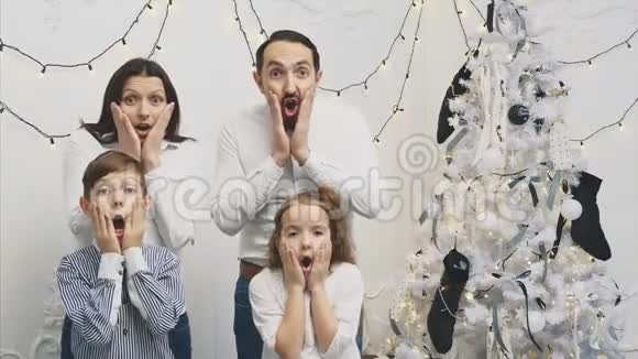 4k视频年轻父母和他们的孩子在新年背景下广泛打开双手脸颊看上去视频的预览图