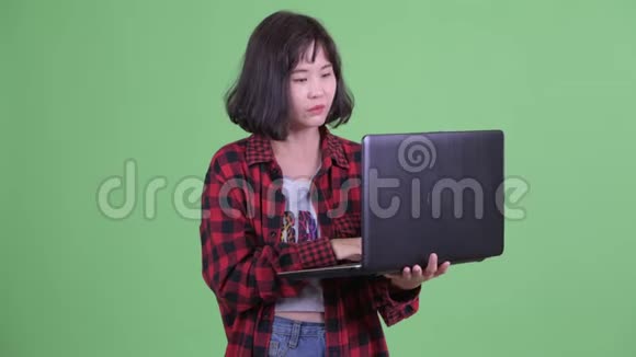 快乐的亚洲时髦女人用手提电脑说话视频的预览图