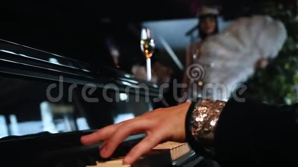主题派对一个男人弹钢琴一个穿着闪闪发光衣服的女人拿起一杯香槟视频的预览图