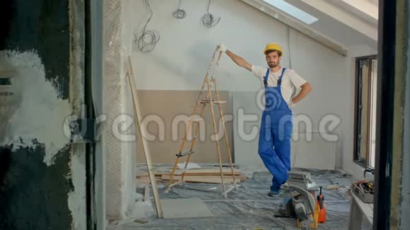 年轻的杂工或建筑工人站在房子里看摄像机视频的预览图