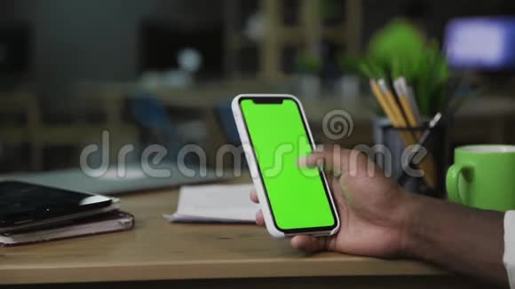 背部特写观看的非洲男子上网使用手机与绿色屏幕视频的预览图