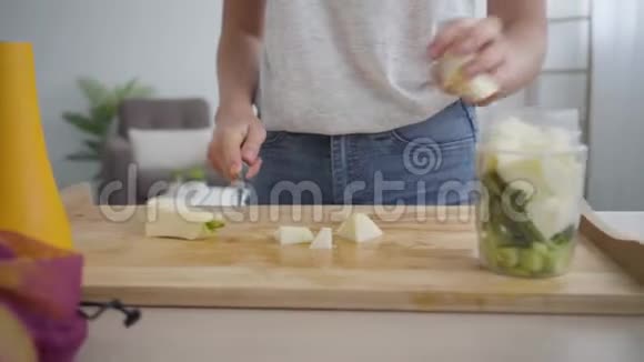年轻女人用锋利的刀切大苹果然后把它放进厨房的碗里概念视频的预览图