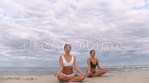 年轻女性在沙滩上慢动作练习莲花姿势瑜伽视频的预览图