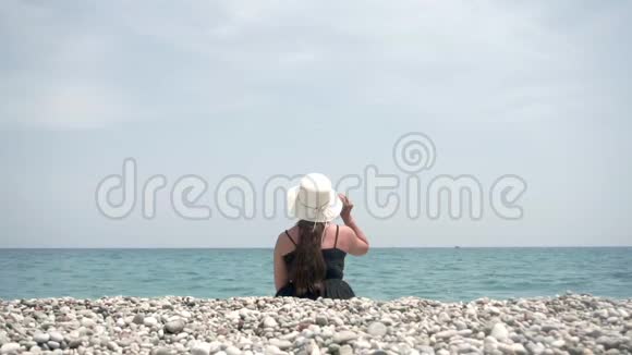 女游客坐在海滩上享受美丽的海景水和阳光视频的预览图
