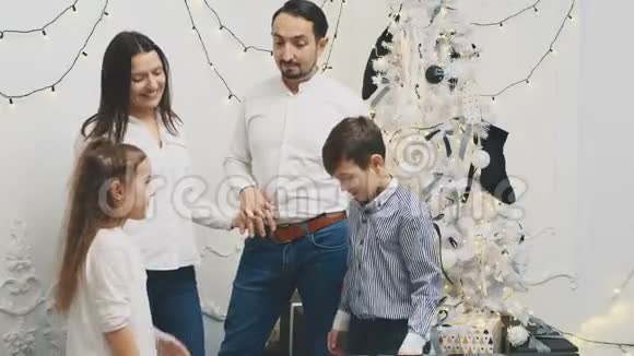 父母和两个兄弟姐妹聚集在圣诞树附近互相转告他们的新年愿望弯曲的手指视频的预览图
