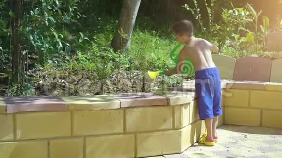 小男孩在花园里给植物浇水视频的预览图