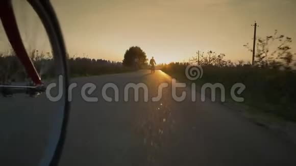 两个骑自行车的人在路上顶着夕阳视频的预览图