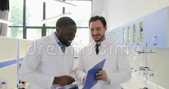 两位科学家拿着实验结果的文件开心地微笑着握手为成功欢呼视频的预览图