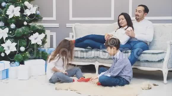 爱的父母看着孩子召唤着雪花坐在沙发上说话微笑视频的预览图