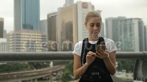 年轻女孩在户外使用智能手机的城市背景视频的预览图