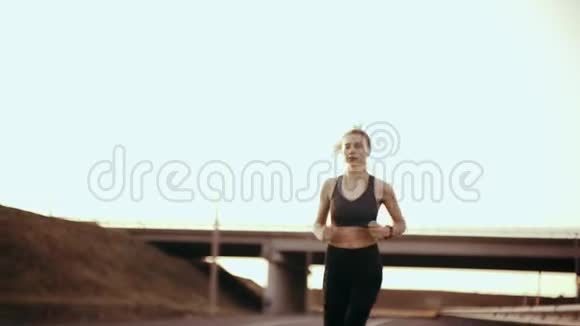 在炎热的一天日落时分一个穿着运动服的女孩正在路上跑步视频的预览图