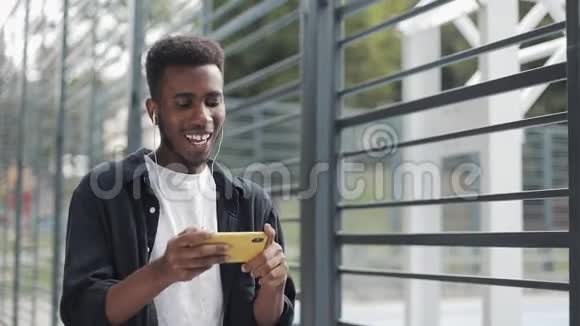 男人用耳机在智能手机上看视频视频的预览图