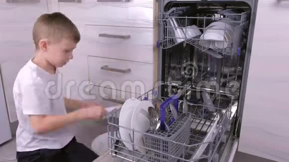 男孩正在厨房里把盘子放进洗碗机里视频的预览图