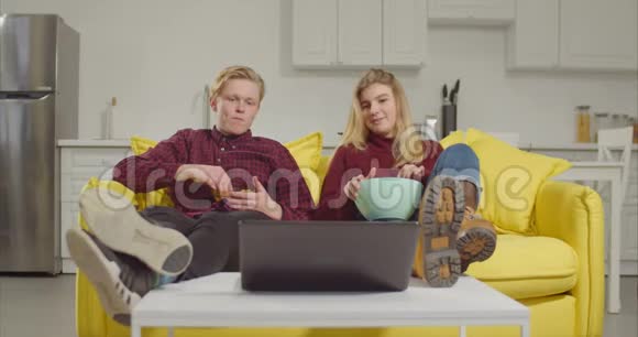 放松的一对夫妇在笔记本电脑上看在线电视视频的预览图