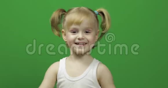 穿白色t恤的快乐小女孩可爱的金发孩子跳舞和做脸视频的预览图