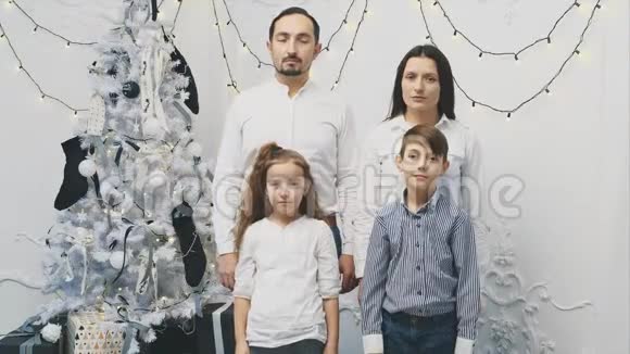 父母和孩子站在圣诞树旁心烦意乱的不堪一击的心情而圣诞节则是微笑和微笑的时候了视频的预览图