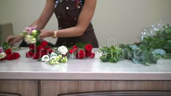 女孩花店把漂亮的花放在桌面上放在花束里小生意视频的预览图