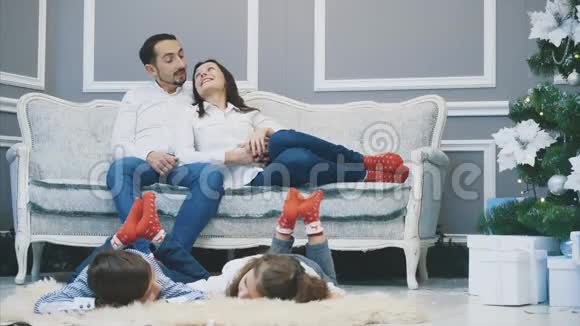 可爱的穿着红袜子的家庭成员正在迎接新年困倦的孩子躺在白色的地毯上视频的预览图