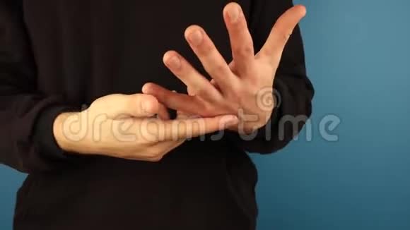 一个穿着黑色连帽衫的男人把手指放在蓝色的背景上保持分数的概念视频的预览图