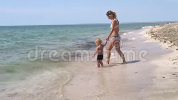 一位母亲和她的孩子在海边的海浪中玩耍视频的预览图