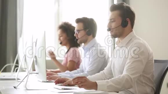 男性呼叫中心代理佩戴无线耳机咨询客户视频的预览图