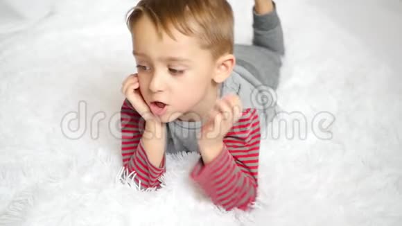一个忧郁的孩子躺在白色的床上动作缓慢视频的预览图