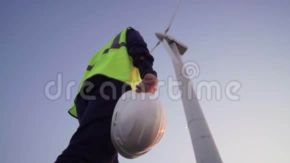 工程师手里拿着一顶白色的头盔向前面的风车走去视频的预览图