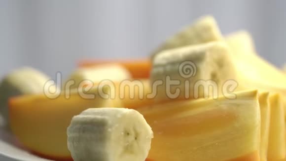 美味的成熟香蕉和柿子片旋转特写视频的预览图