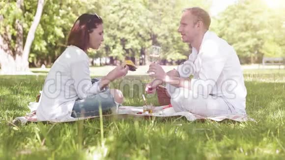 情侣在公园野餐女人吃芒果男人喝葡萄酒视频的预览图