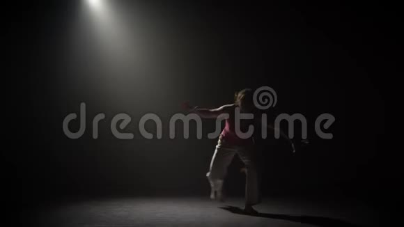 女练习卡波伊拉在黑暗中聚光灯下在演播室视频的预览图
