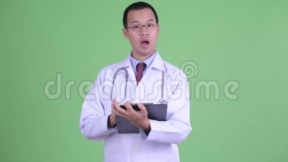 戴眼镜的亚洲快乐男医生拿着剪贴板说话视频的预览图