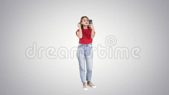美丽的年轻女子使用睫毛膏并在她的智能手机梯度背景视频的预览图