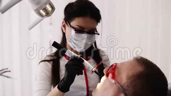女性医生和男性患者戴护橙眼镜在现代牙科ocabinet牙医正在做视频的预览图