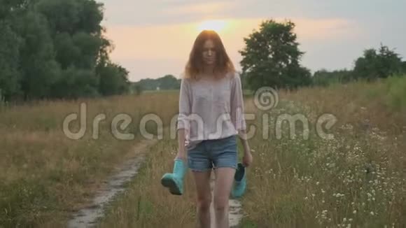 小女孩走在农村的路上手里拿着靴子穿脏衣服的快乐孩子视频的预览图