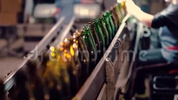 啤酒厂的一名员工从传送带上捡起有缺陷的瓶子视频的预览图