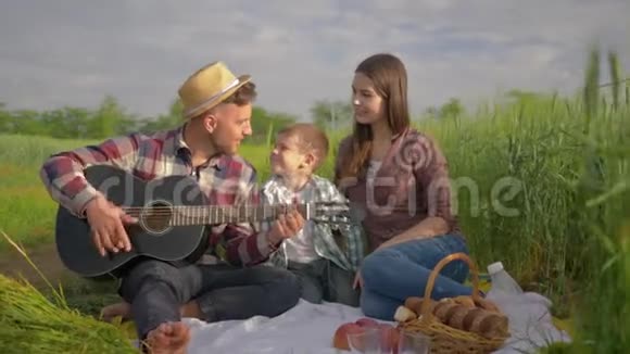 家庭娱乐快乐的男人演奏乐器女孩带着孩子唱歌和拍手放松野餐视频的预览图