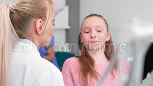 牙医在牙医诊所和十几岁的女孩和她爸爸谈话视频的预览图