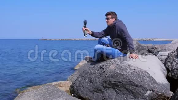 人游客谈智能手机视频聊天海上小鼎坐石上视频的预览图