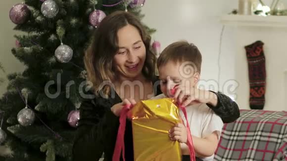 可爱快乐兴奋的妈妈和儿子在一个漂亮的房间里打开了一个圣诞礼盒视频的预览图