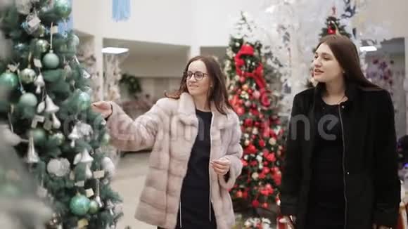 商店里的两个女人的圣诞装饰考虑了人造圣诞树和圣诞装饰视频的预览图